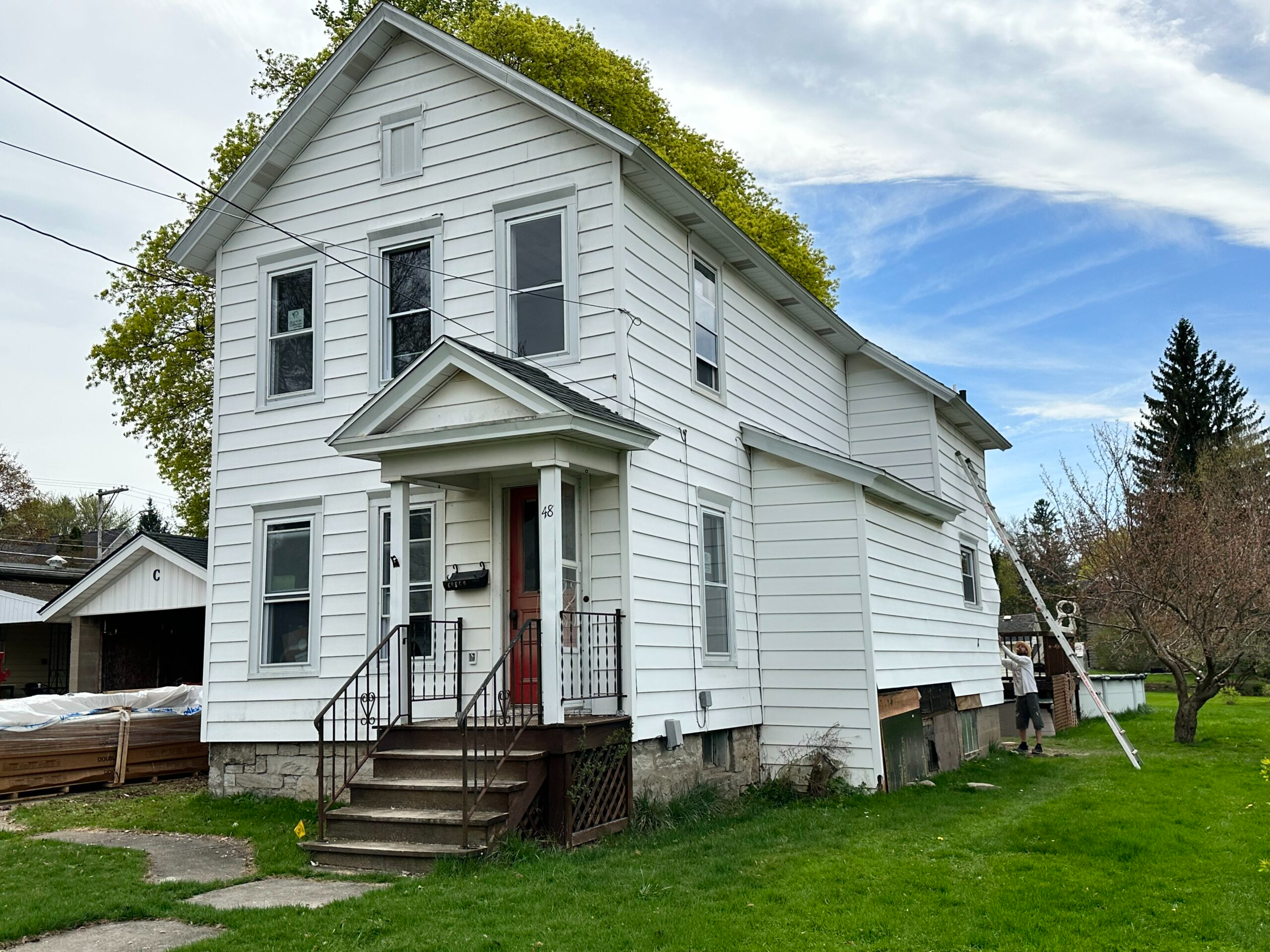 Before photo of a two-story residential home in Auburn, NY undergoing siding removal and exterior preparation by WeBuild CNY contractors
