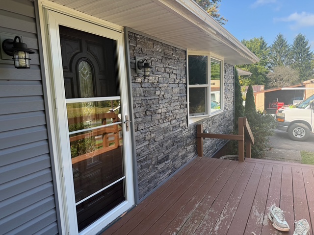Completed exterior remodel in Port Byron, NY featuring new Flagstone vinyl siding, new construction windows, and Cascade River faux stone accents by WeBuild CNY