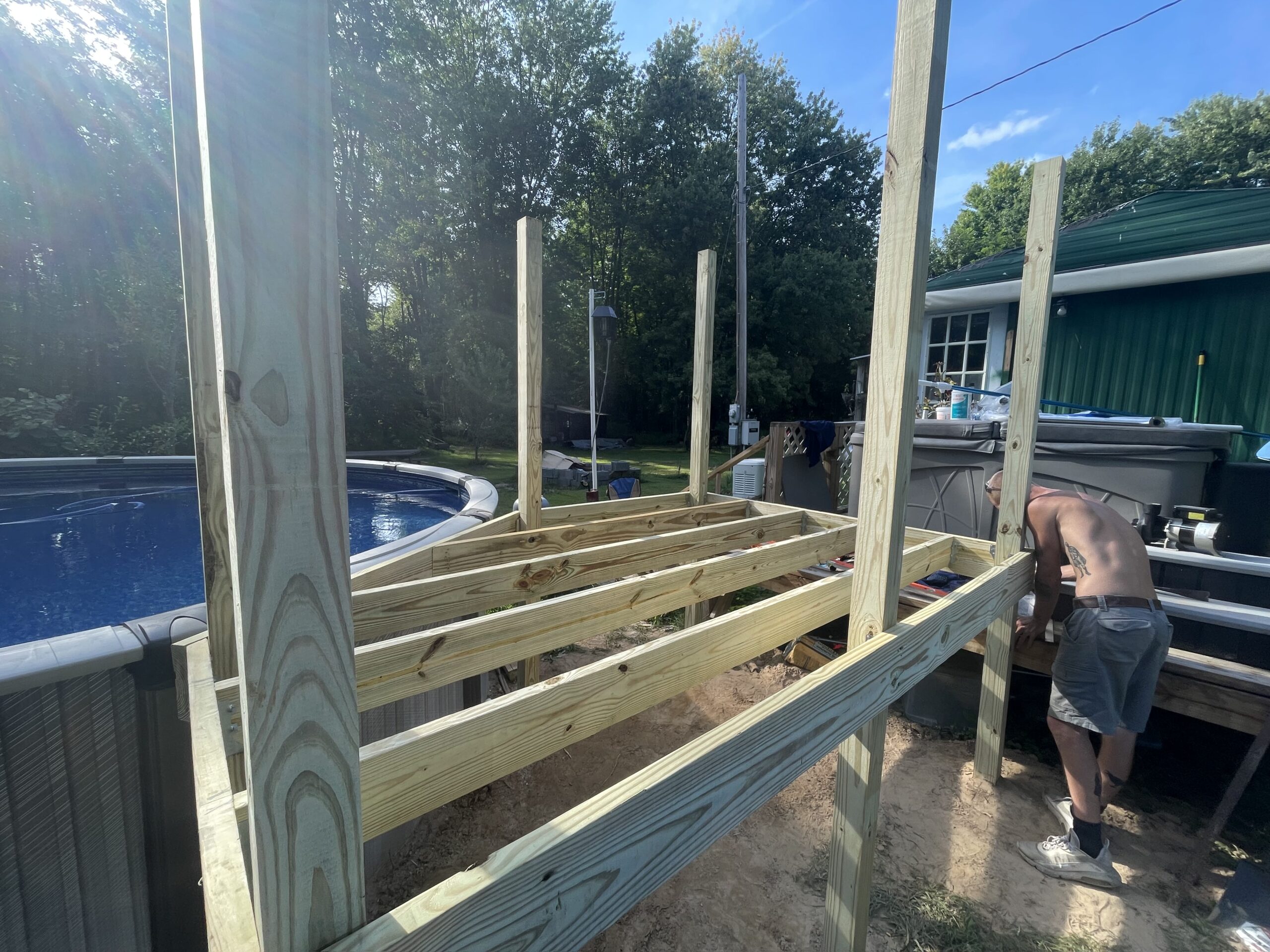 WeBuild CNY deck builders laying pressure-treated wood decking around a residential pool in Cayuga County